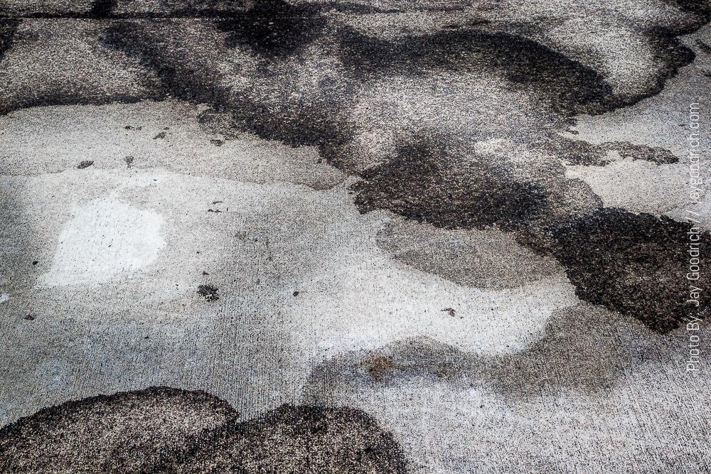 A black and white image of water puddles on a concrete floor.
