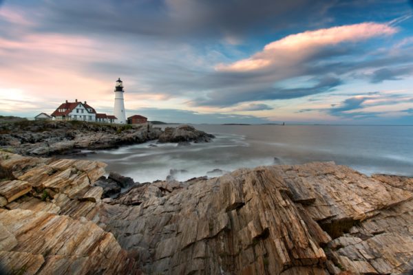 A lighthouse sits on top of a rocky cliff.