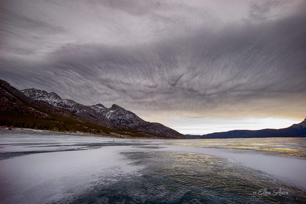 Photo of Frozen Lake with Mountains and Cloudy Sky in the Backround