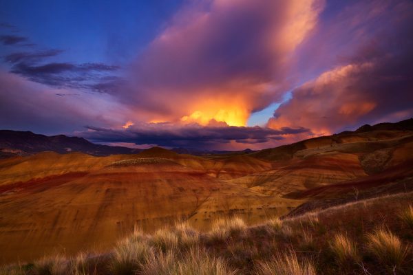 Sunset over colorful hills with clouds.