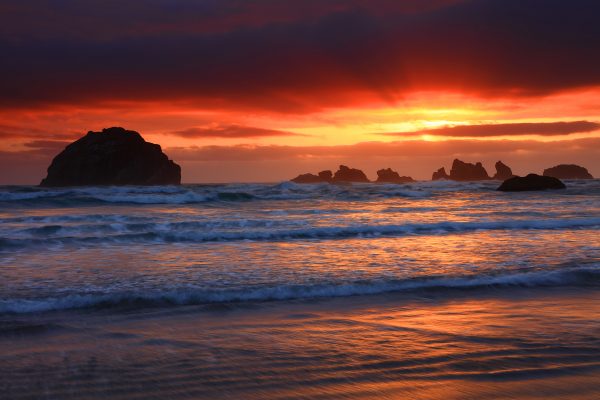 Silhouetted rocks at sunset over the ocean.