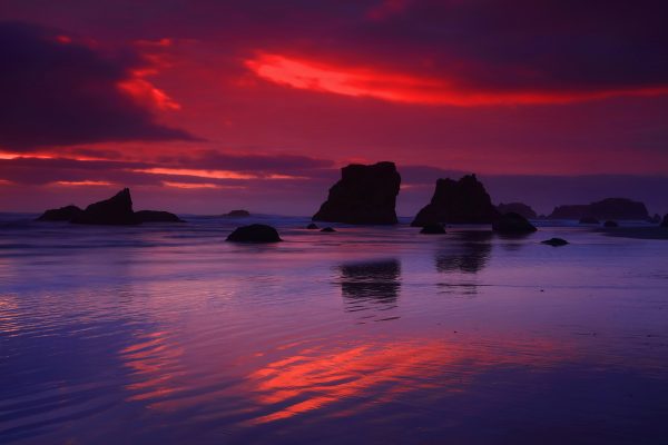 Silhouetted rocks at sunset on the beach.