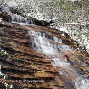 Waterfall cascading over snow-covered rocks.