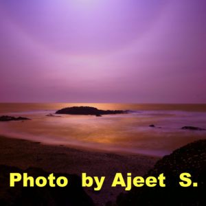 Purple sunset over a rocky shore.