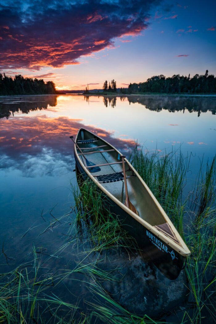 Canoe on calm lake at sunrise.