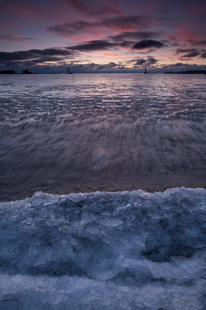 Frozen shoreline with distant lighthouses.