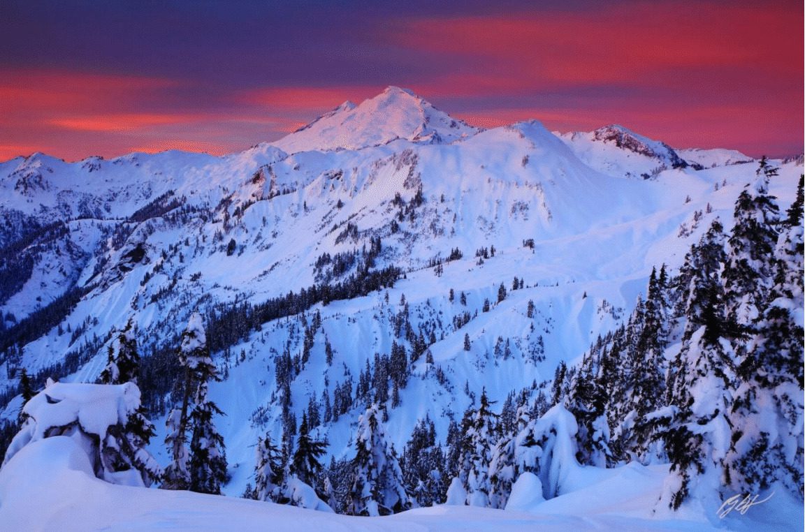 Snowy mountain range with pink sky at sunset.