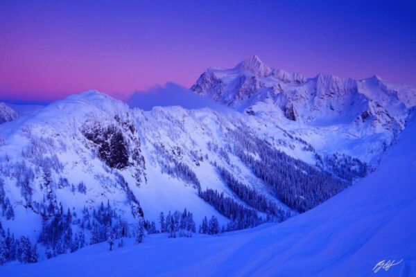 Snow-capped mountains at sunset in purple hues.